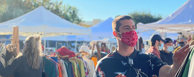 Man wearing a red face mask shopping at an outdoor market